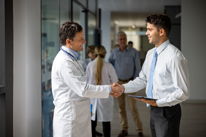 A doctor and healthcare administrator shake hands
