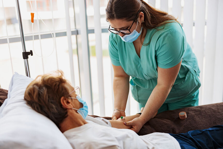 A registered nurse places an IV drip on a patient