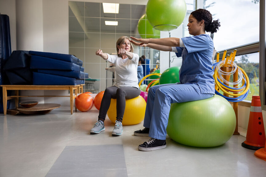 A female occupational therapist works with a patient using swiss exercise balls