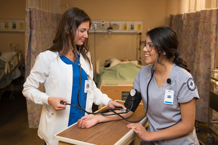 Two female nursing students practicing taking blood pressure readings