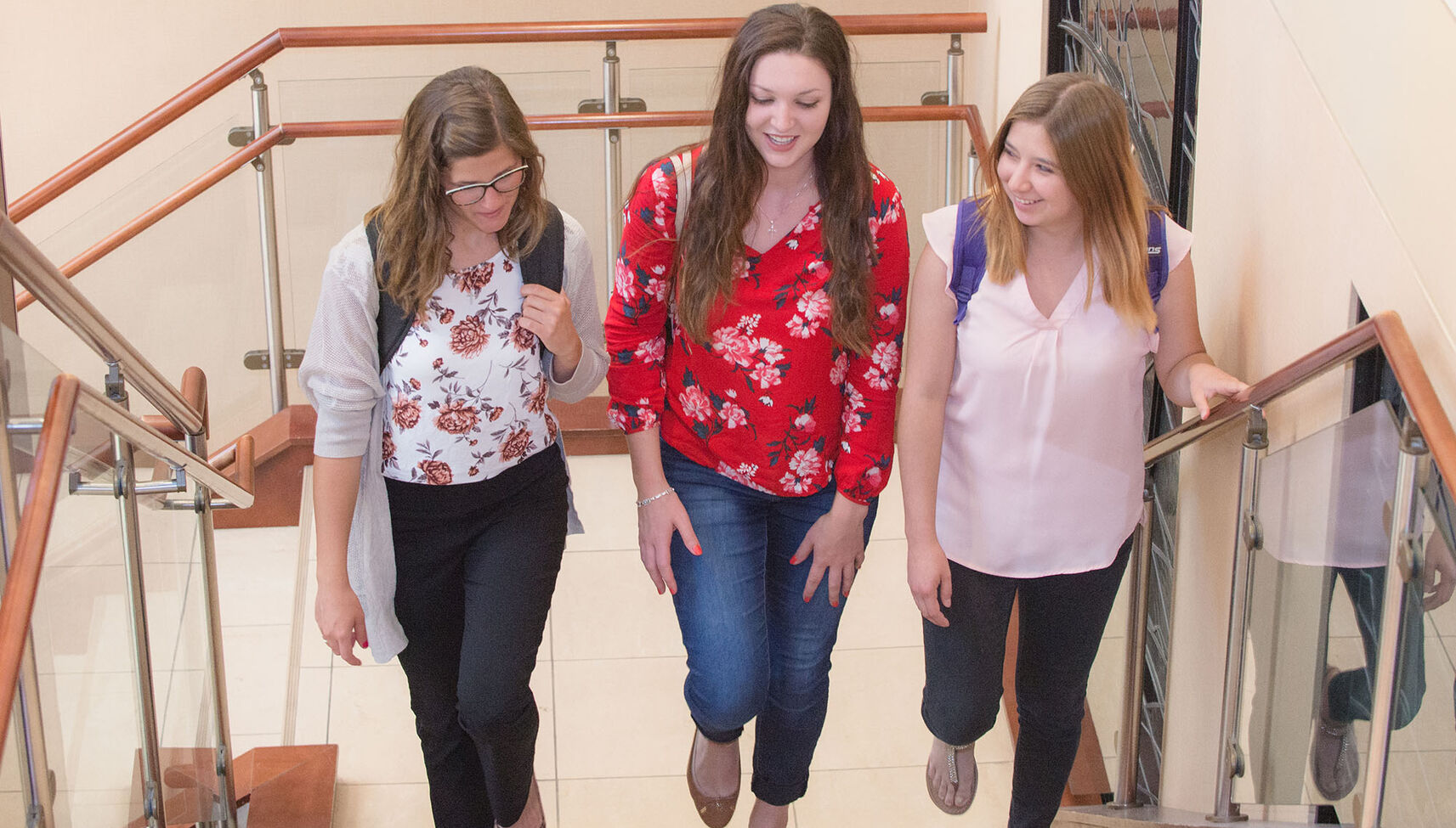 Three female students walking up the stairs together.
