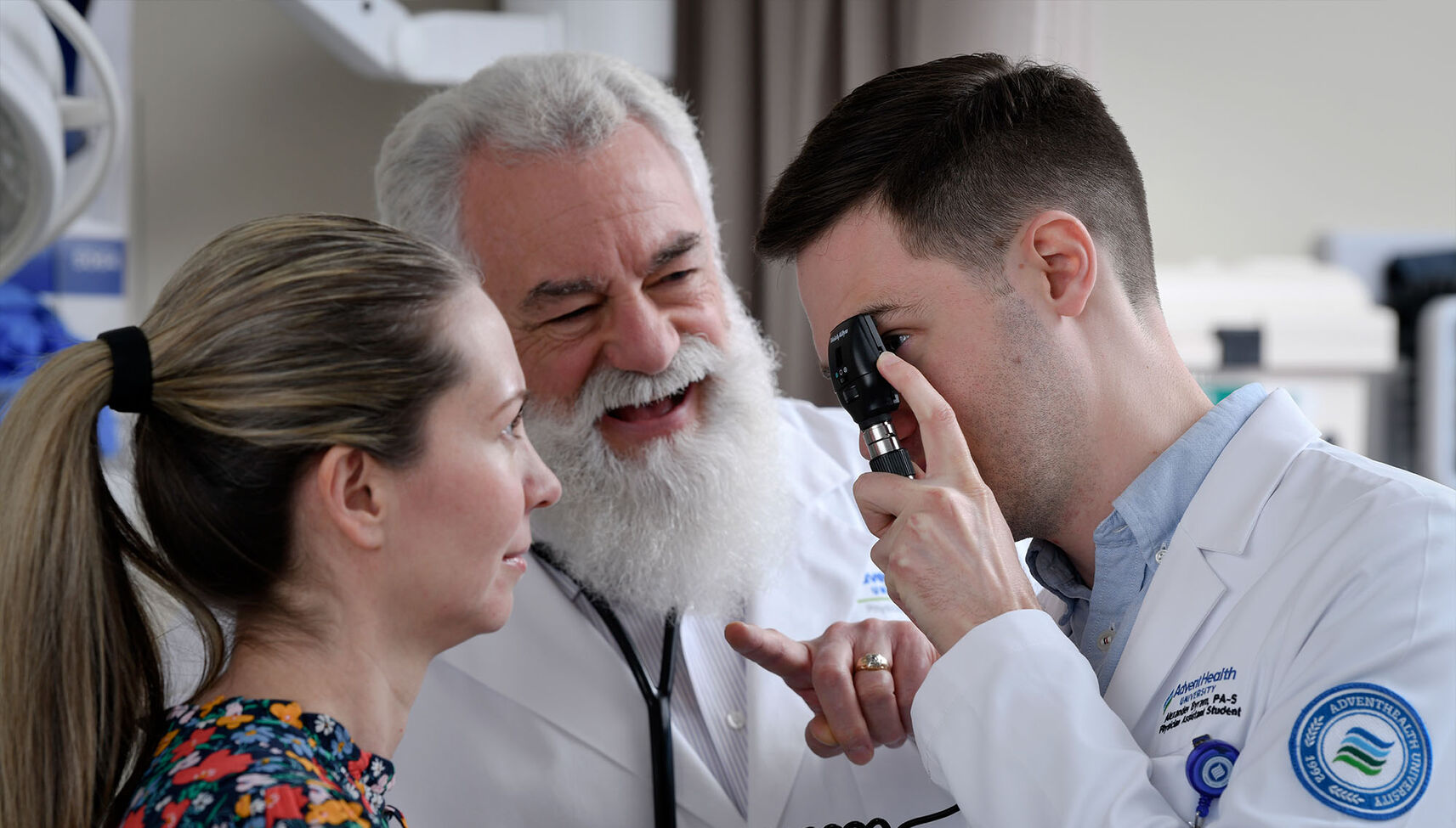 A physician assistant student examines a patient under the supervision of a faculty member