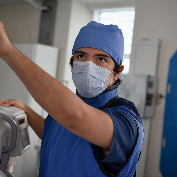 A radiography student positioning the arm of an x-ray machine