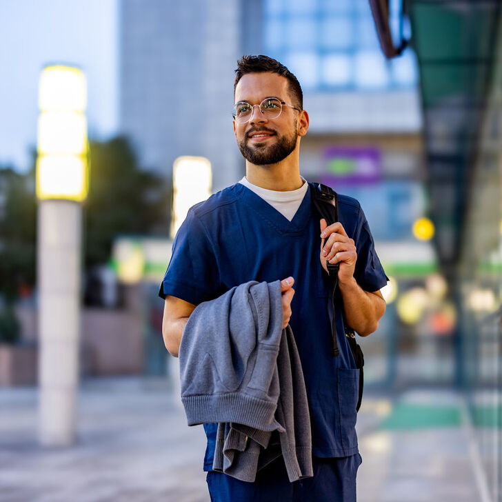 A male travel nurse standing outside a buidling