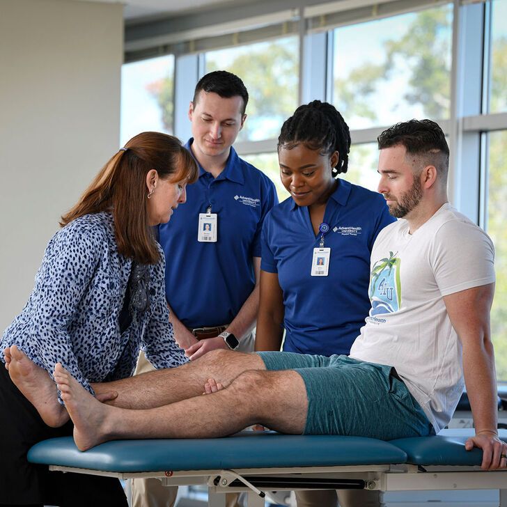 Physical therapy faculty and students practicing on patient table